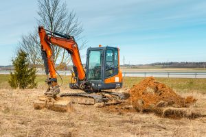 Small orange excavator digging in a construction site.