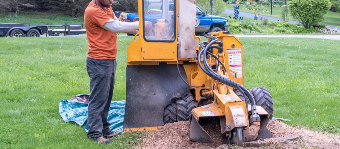 Excavator operator operating heavy machinery on a residential lawn.